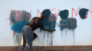 A caretaker of a building attempts to rub off anti-government graffiti in Harare, Zimbabwe, Sept. 6, 2016. / Photo Credit: AP